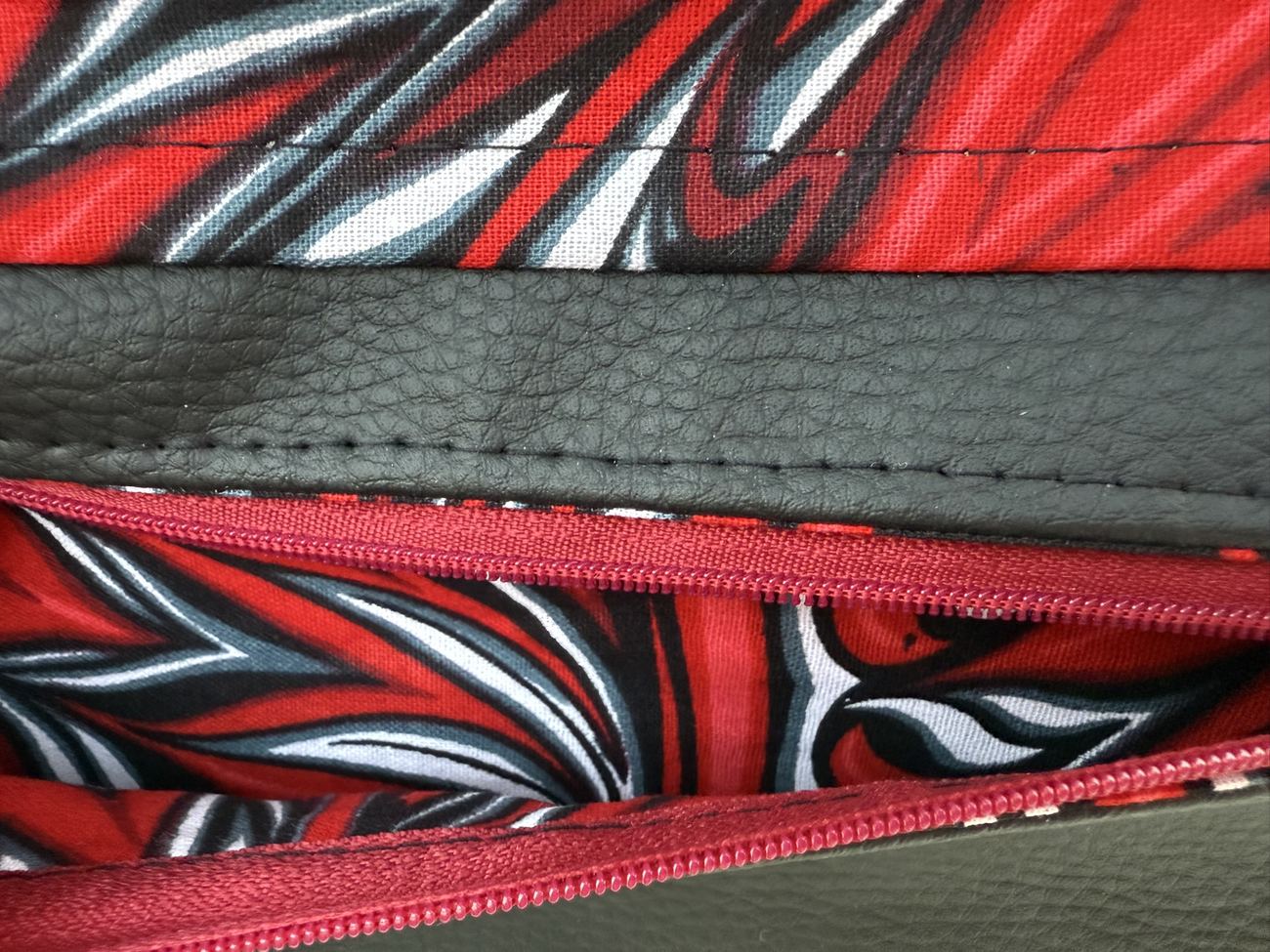 Poche zippée bordée de rouge sur un sac Quadrille noir, doublure wax rouge